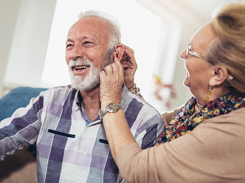 woman helping man with hearing aid