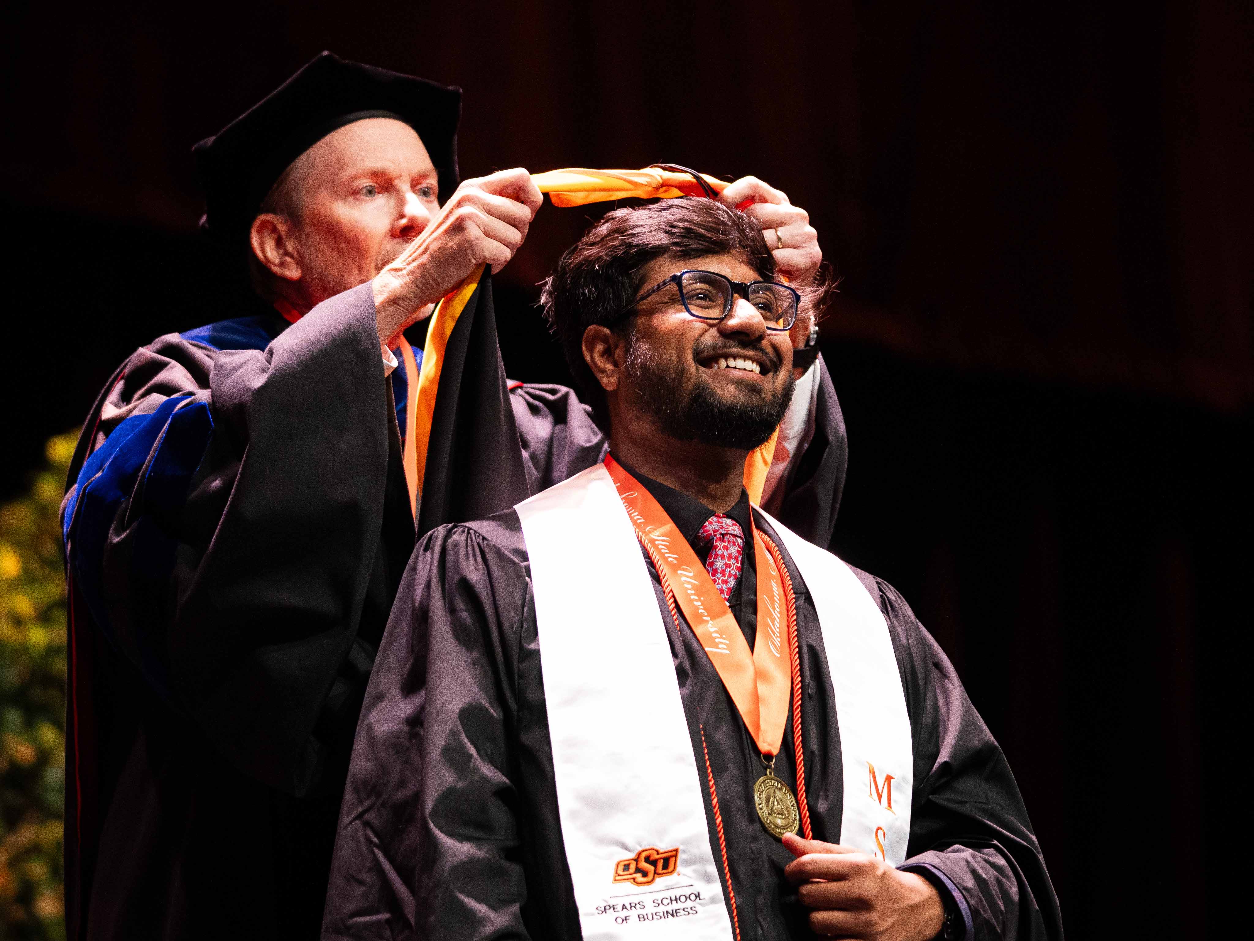 A male student is hooded at graduation.