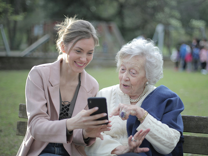 Woman and her daughter on a bench looking at their phone